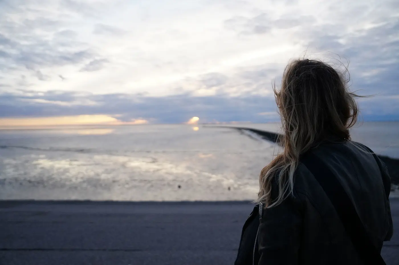 Eine Frau blick auf das Meer und die weiten Himmel. Hier finden unsere Patientinnen Ruhe und Zeit zum Durchatmen, um neue Kraft zu sammeln.