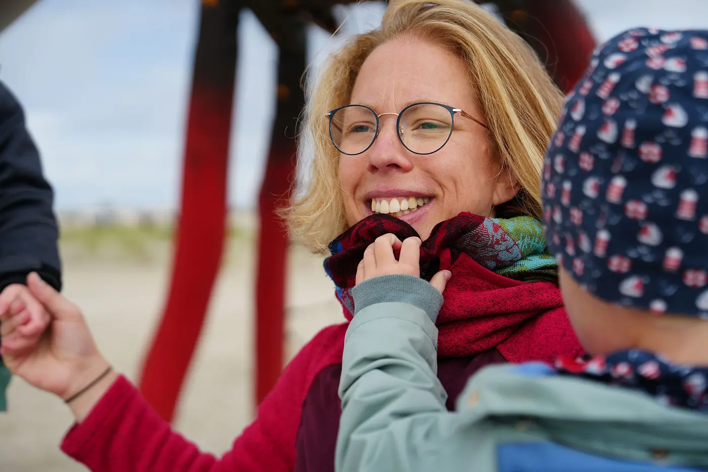 Frau lacht in die Kamera, sie hat ein Kind auf dem Arm